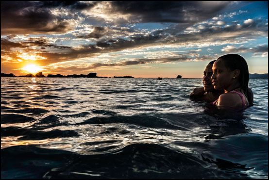 Et forelsket par nyter den vakre solnedgangen ved Playa Anchon